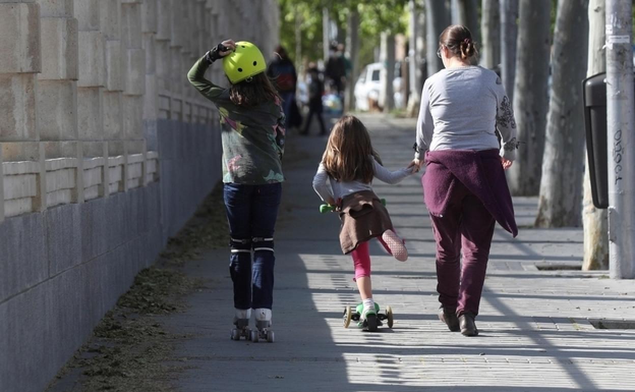 Una madre pasea con sus dos hijas por un parque de Madrid.