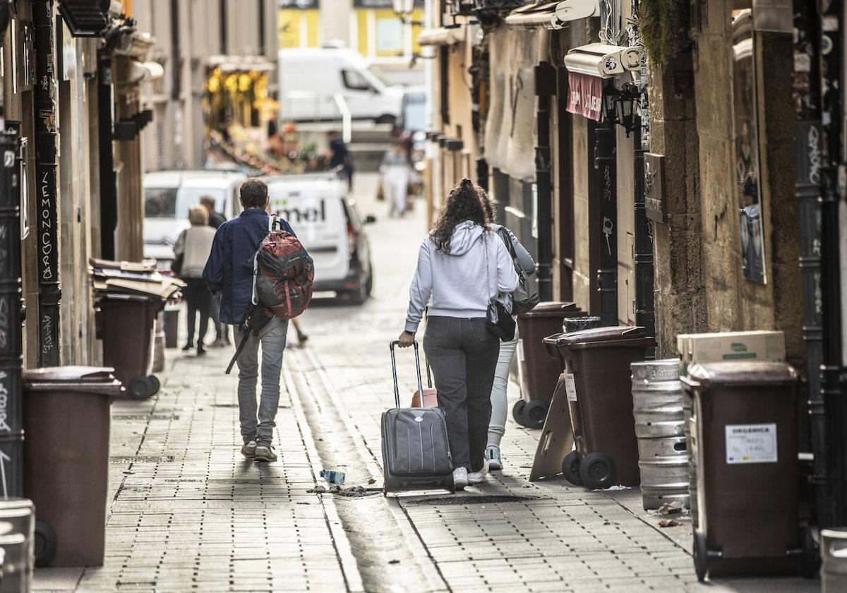 Tres turistas cruzan la calle Laurel a priemra hora de la mañana.