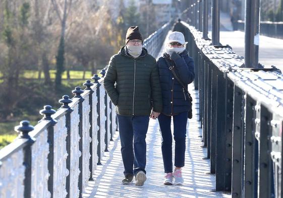 Dos personas caminan en la mañana de ayer por el puente de hierro de Logroño.