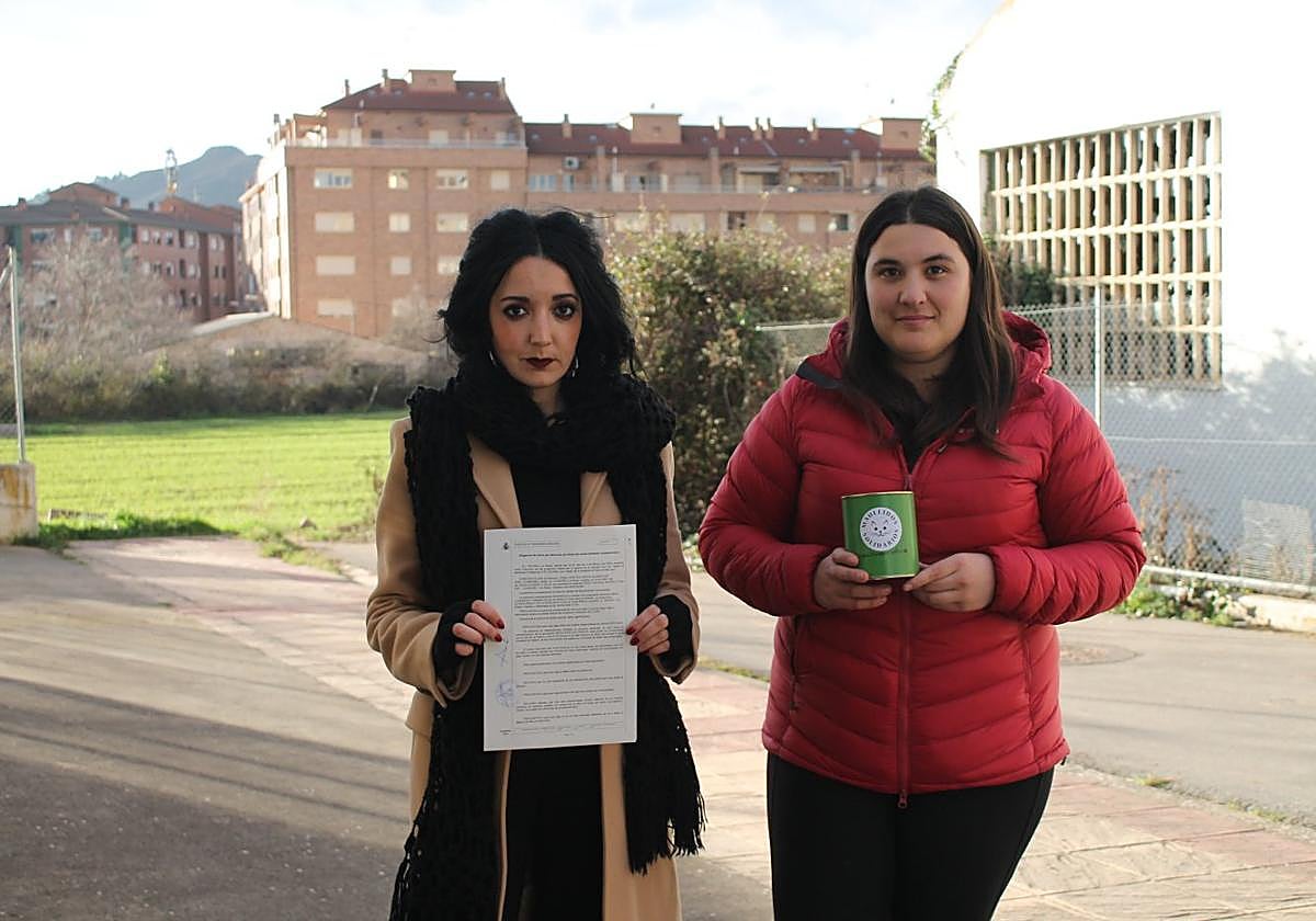 Cristina y Verónica, de Maullidos Solidarios, posan en el lugar del crimen con la denuncia presentada y una hucha para recaudar fondos.