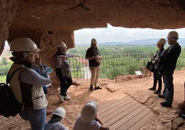 Un grupo de personas escucha las explicaciones del recorrido guiado de las cuevas, con el valle del Najerilla como bello telón de fondo.