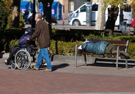 Una persona sin techo duerme en uno de los bancos del Espolón.