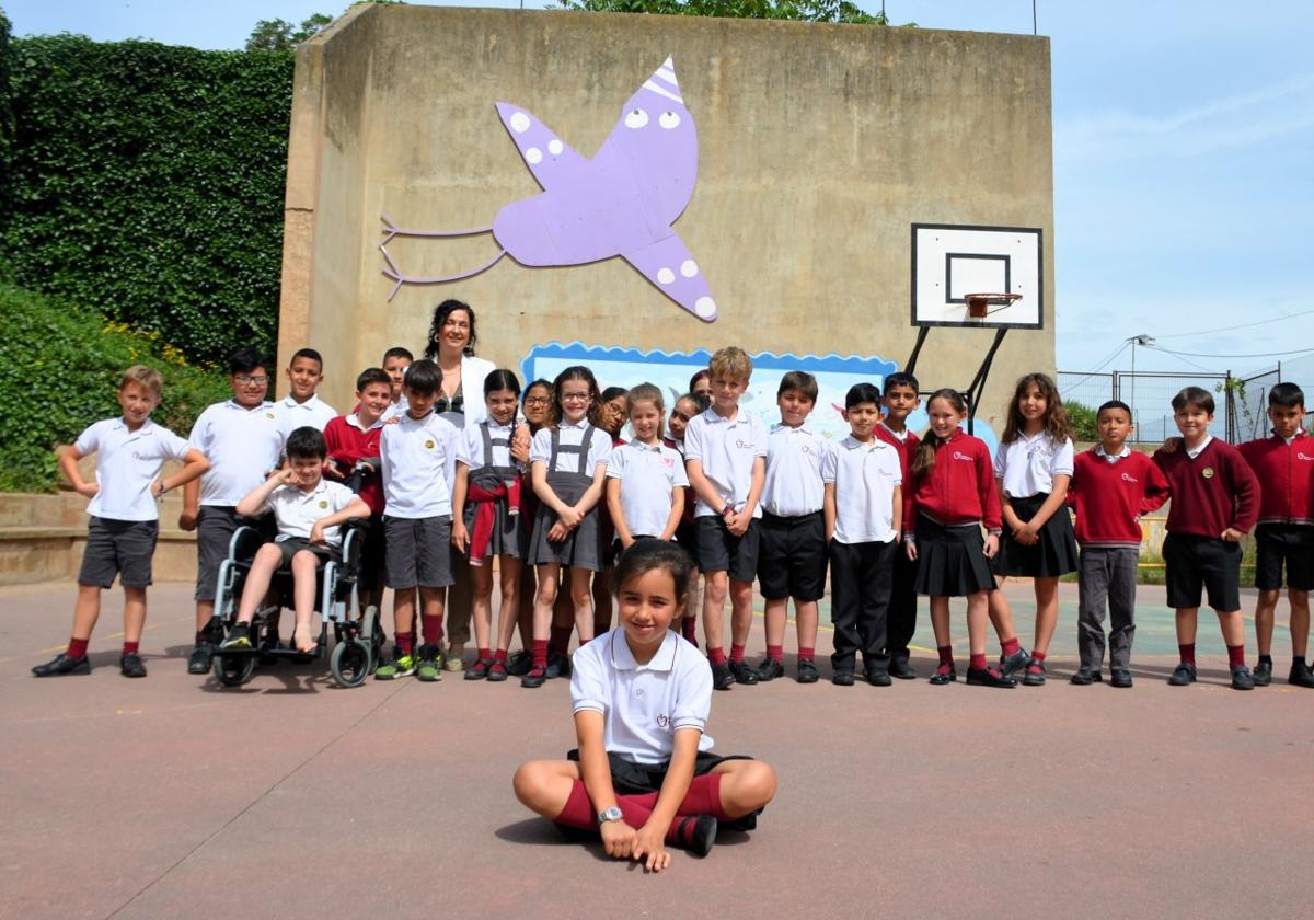 Elvira Alonso posa delante de sus compañeros y del 'pájaro morado' que dibujó para Concéntrico y que se ha colocado en el patio de su colegio.