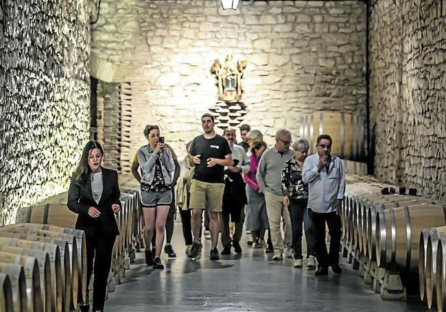 Un grupo de visitantes recorre, entre barricas, la sala de la Virgen en las instalaciones de Bodegas Franco-Españolas.