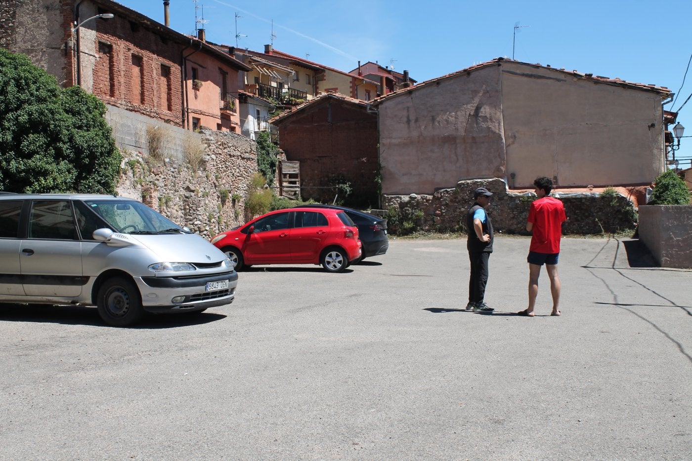 Dos vecinos emilianenses charlan en el solar, actualmente un aparcamiento, en el que será construido el futuro albergue de sesenta plazas.