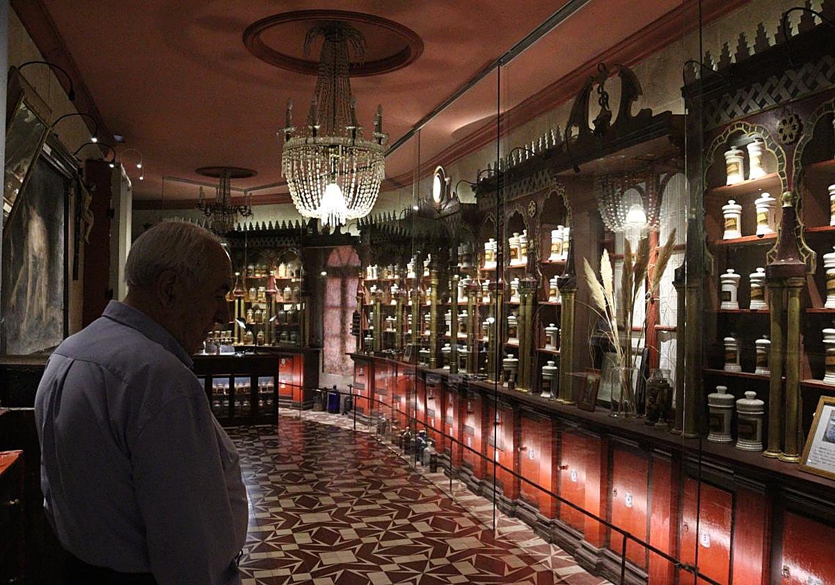 El padre Ángel en la botica de la ermita observa los frascos de la exposición.