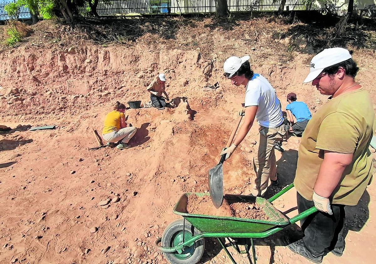 Imagen secundaria 1 - Labores de limpieza en la necrópolis y retirada de tierra y piedras en la excavación de La Clínica(Izq.). Alumnos junto a los restos de estructuras de época romana. 