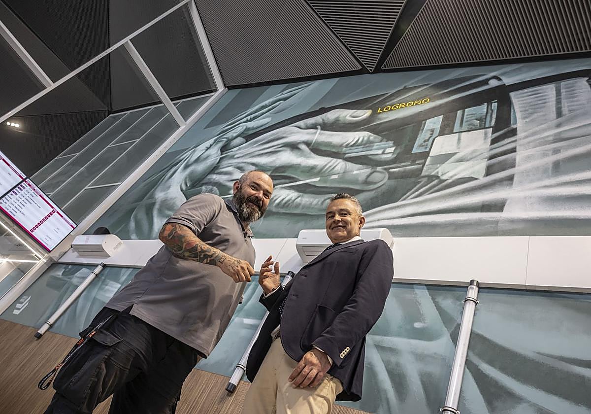 Carlos Corres con Conrado Escobar, con el mural de la estación de fondo