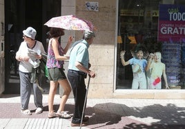 Dos personas se protegen del sol con un paraguas.