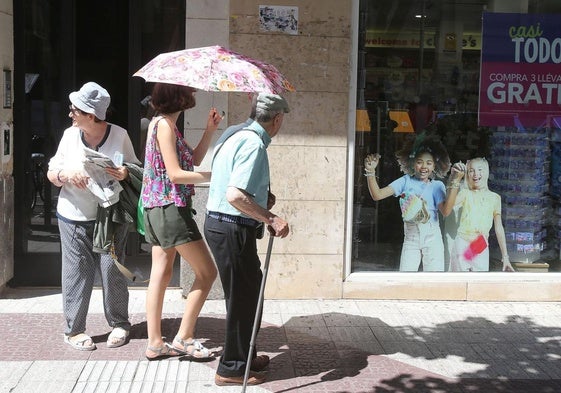 Dos personas se protegen del sol con un paraguas.