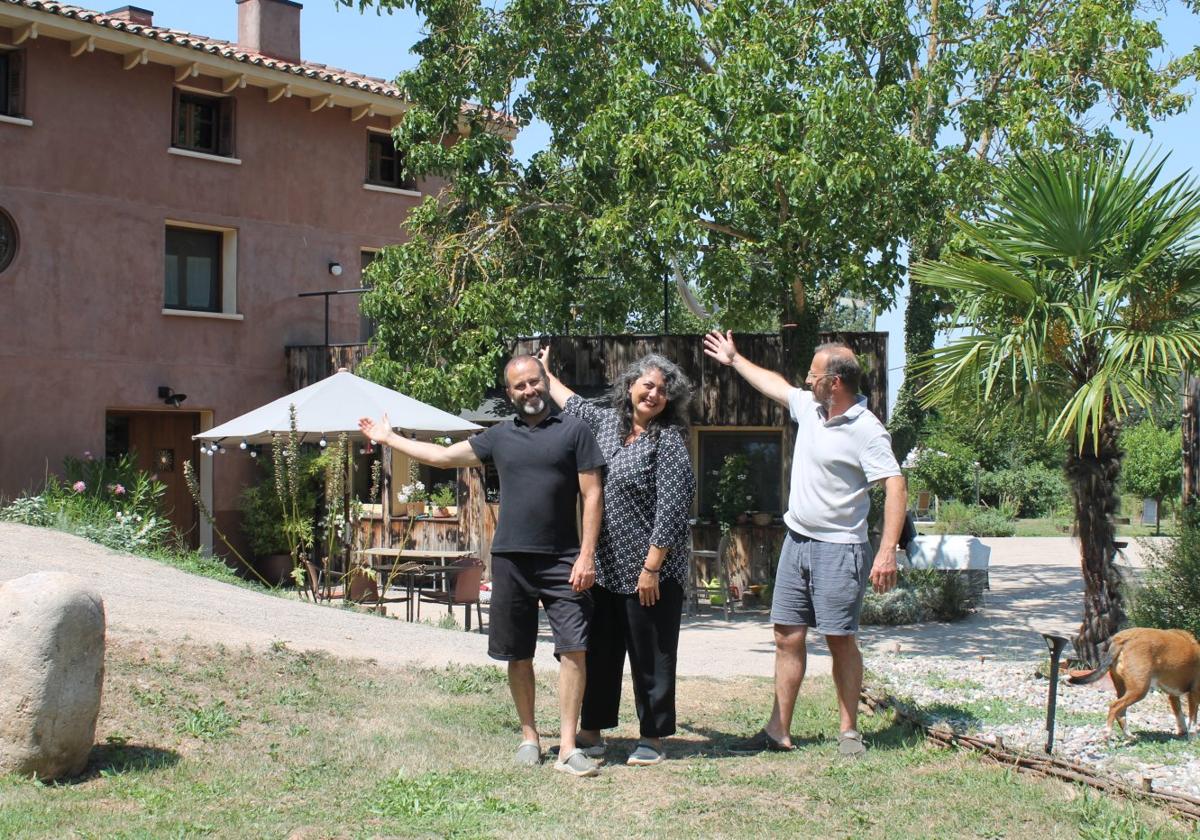José Luis (izquierda), Pilar (centro) y Gustavo (derecha) posan en el jardín de La Casa del Agua señalando hacia el alojamiento rural.