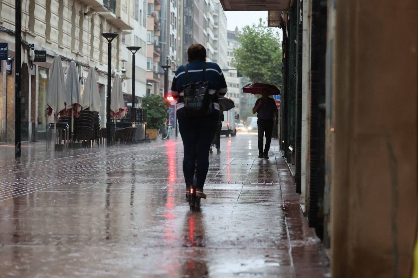 Varias personas transitan por la calle Calvo Sotelo de Logroño bajo la lluvia de este jueves.