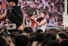 Un joven, en plena celebración, con las pantallas habilitadas para el público de fondo.