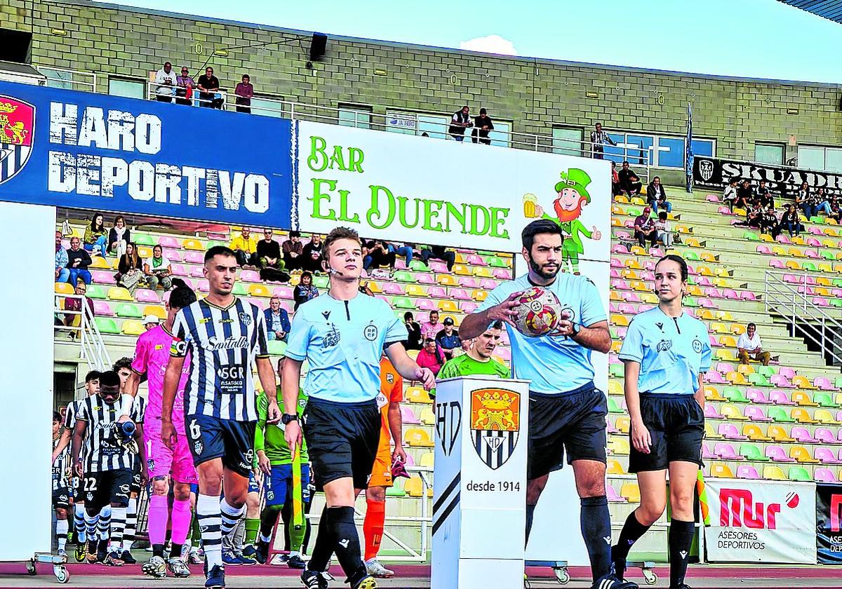 El trío arbitral y los jugadores del Haro y el Berceo saliendo al terreno de juego el domingo en el estadio Luis de la Fuente.