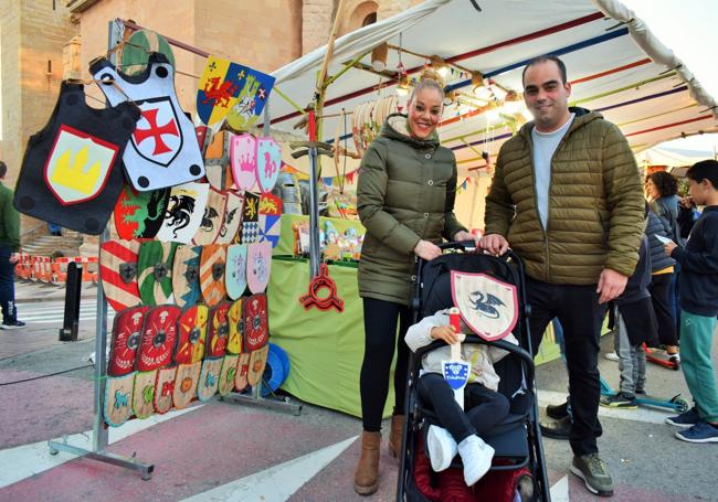 Unos padres compran una espada y un escudo de madera a su hijo.