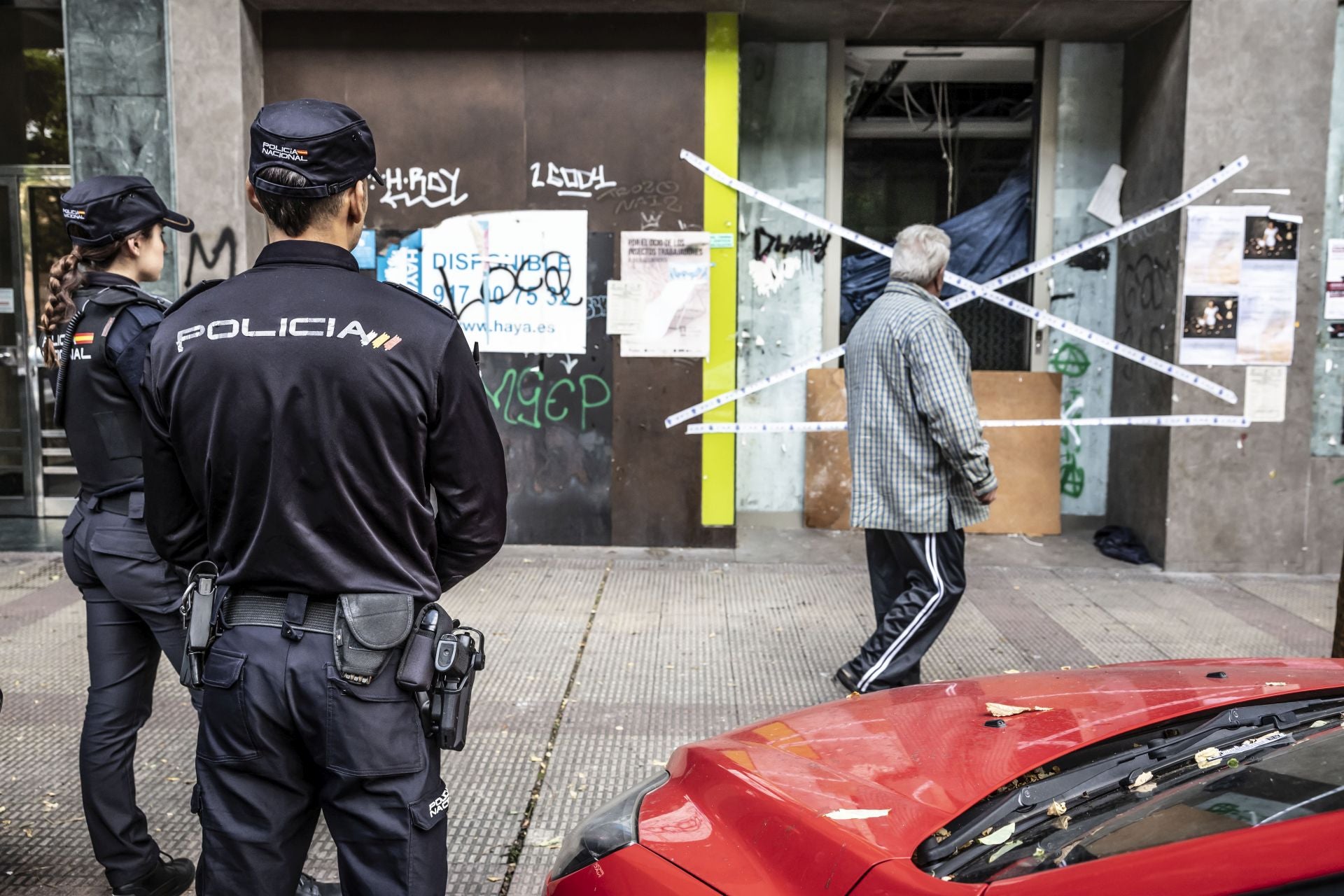 Un vecino pasa junto al lugar del crimen ante la mirada de dos agentes de la Policía Nacional