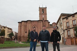 Robles y Perrino, de Cluny Ibérica, posan junto al alcalde Salaverri (centro) con el monasterio al fondo.