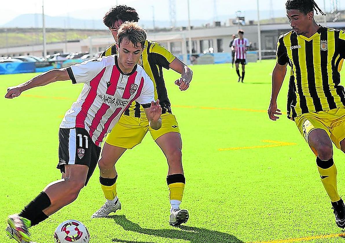 Íker Pérez intenta deshacerse de dos jugadores del Vianés.