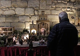 Un hombre contempla el belén con la réplica de la basílica de la Vega.
