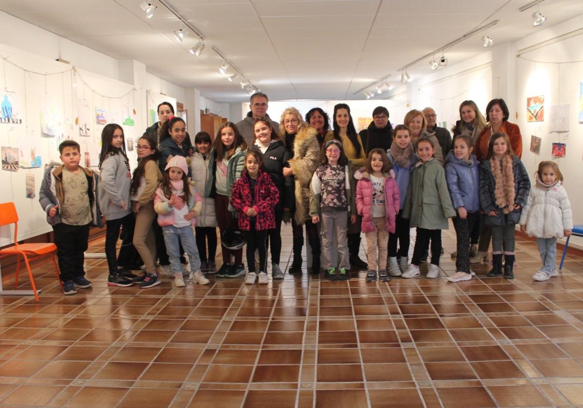 Un amplio grupo de niños participantes posan, acompañados de sus familias, en la salita de otoño.