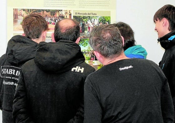 Una familia contempla el panel que explica la tradición del veraniego Mercado del Trato ventosino.