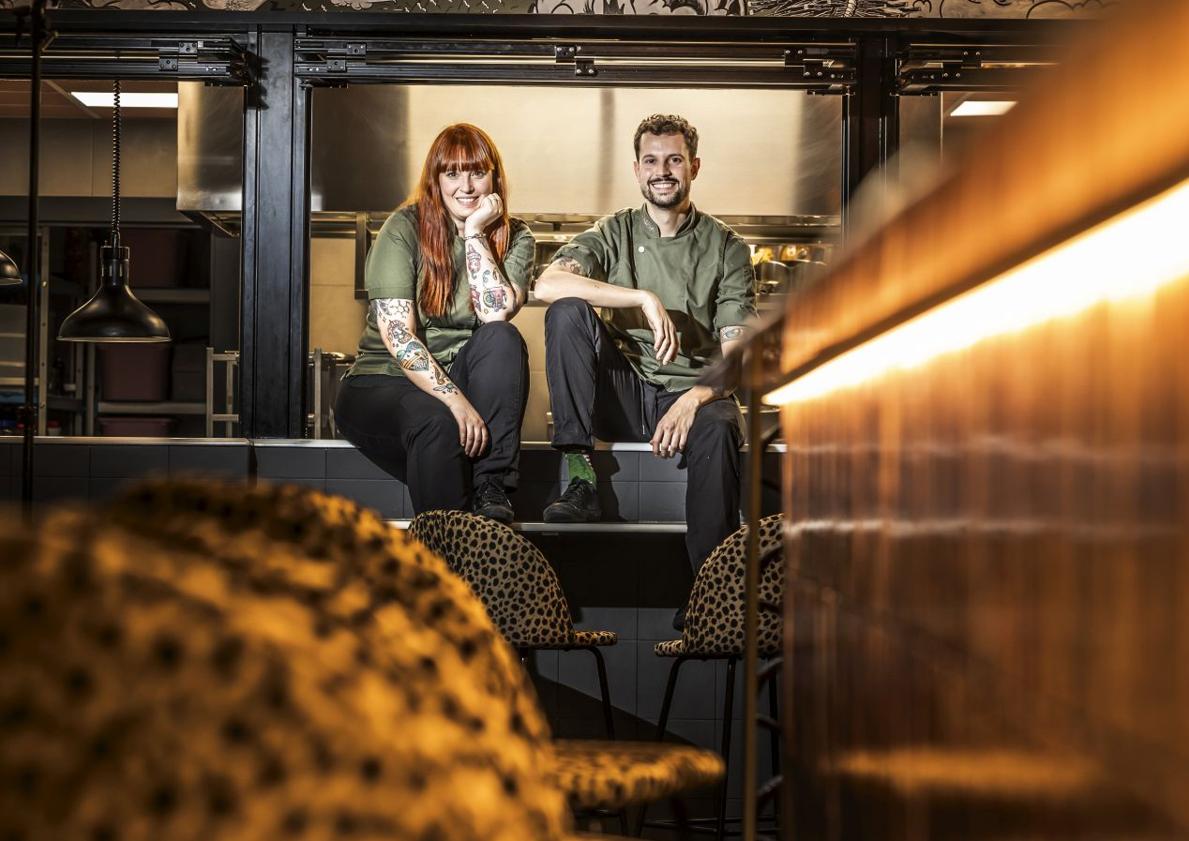 Imagen principal - Beatriz y Rodrigo posan en el mostrador de la cocina abierta de su restaurante | Unos curiosos baños y una mesa ya montada.