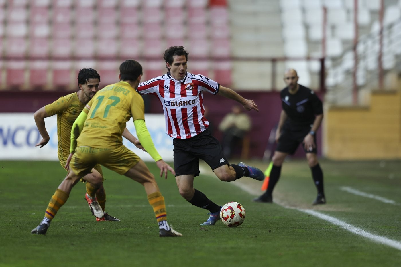 Nacho Ruiz intenta salir con el balón controlado entre dos defensas rivales.