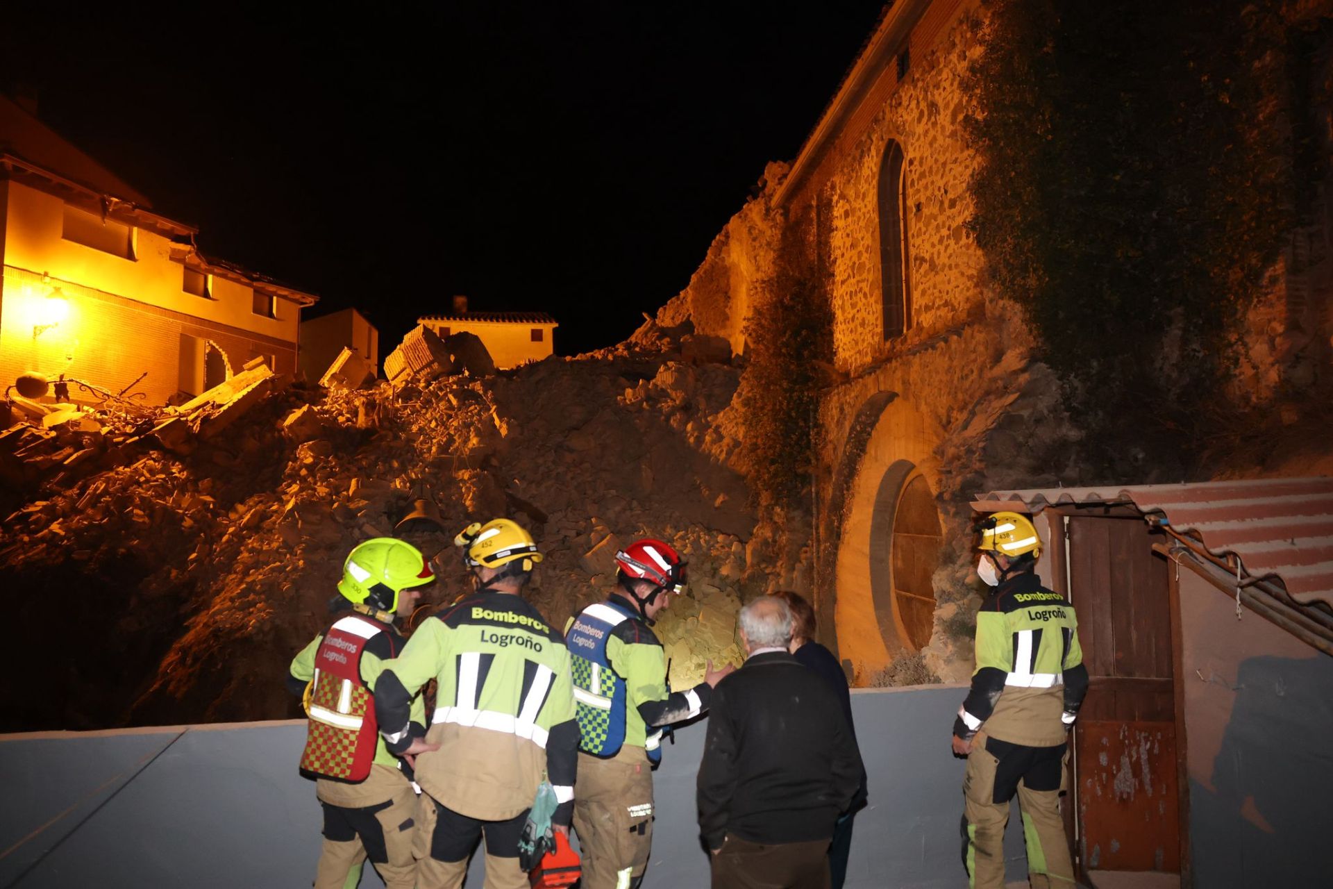 Bomberos y vecinos, junto a los escombros en los que se ha convertido la torre.