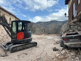 Una retroexcavadora junto a uno de los coches extraídos de la calle La Barga.