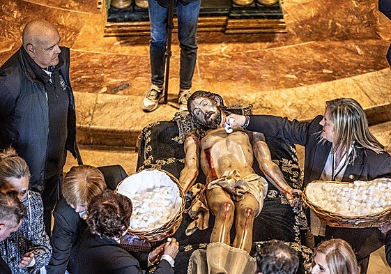 La hermana mayordomo, Ana Idoya García, acaricia el rostro del Cristo, mientras las camareras pasan el algodón por el cuerpo del yacente.