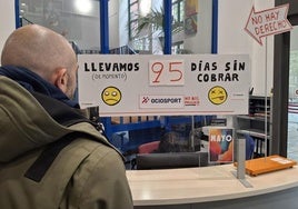 Un hombre observa el cartel de protesta por los impagos de los trabajadores de Ocio Sport en La Gota de Leche de Logroño.