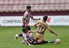 Lamadrid y Castañeda, desde el suelo, intentan arrebatarle el balón a Zubiria, del Eibar B.