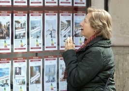 Una mujer observa los anuncios sobre alquileres en una inmobiliaria.