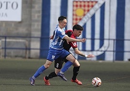 David Medrano y Adrián Ruiz pelean por hacerse con la posesión del balón en el partido de ida de la semifinal de la fase regional de ascenso.