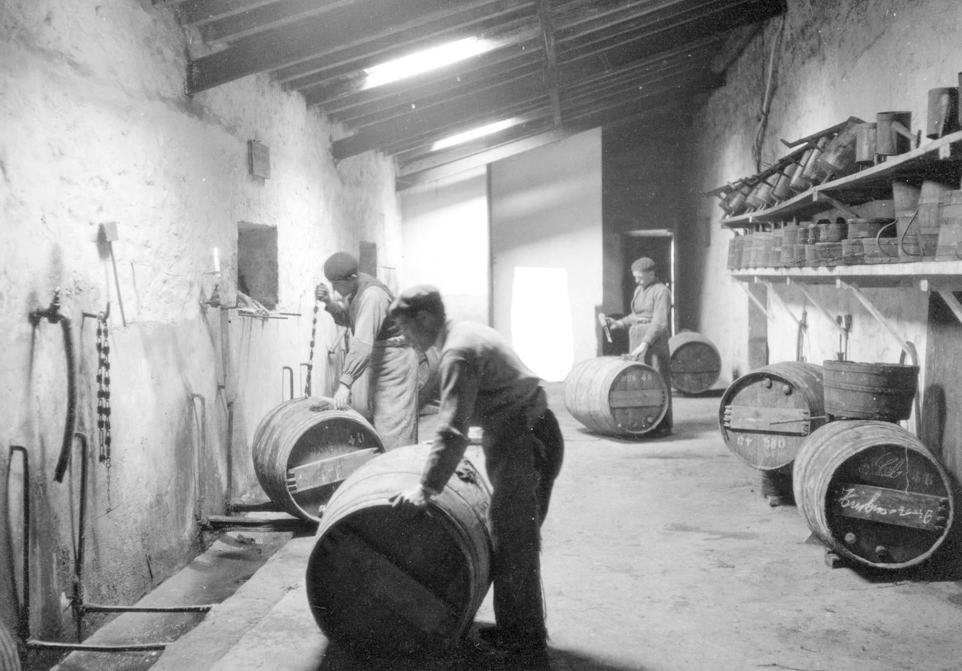 Trabajadores limpiando y reparando barricas.