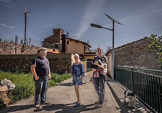Luis Argaiz, Isabel y Bruno posan en Carbonera, ante las farolas de energía fotovoltaica y el aerogenerador doméstico de un vecino.