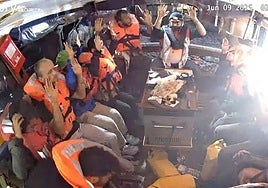 Manos arriba. Una fuerte luz ilumina el velero 'Madleen' mientras sus tripulantes levantan las manos en señal de rendición.