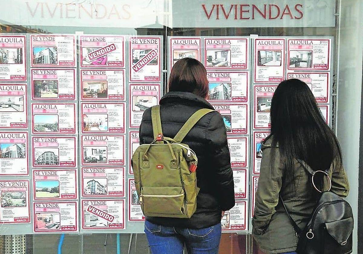 Dos mujeres consultan los anuncios de una inmobiaria.