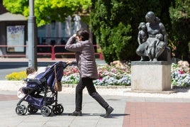 Una mujer pasa con un carro por delante del Monumento a la madre.