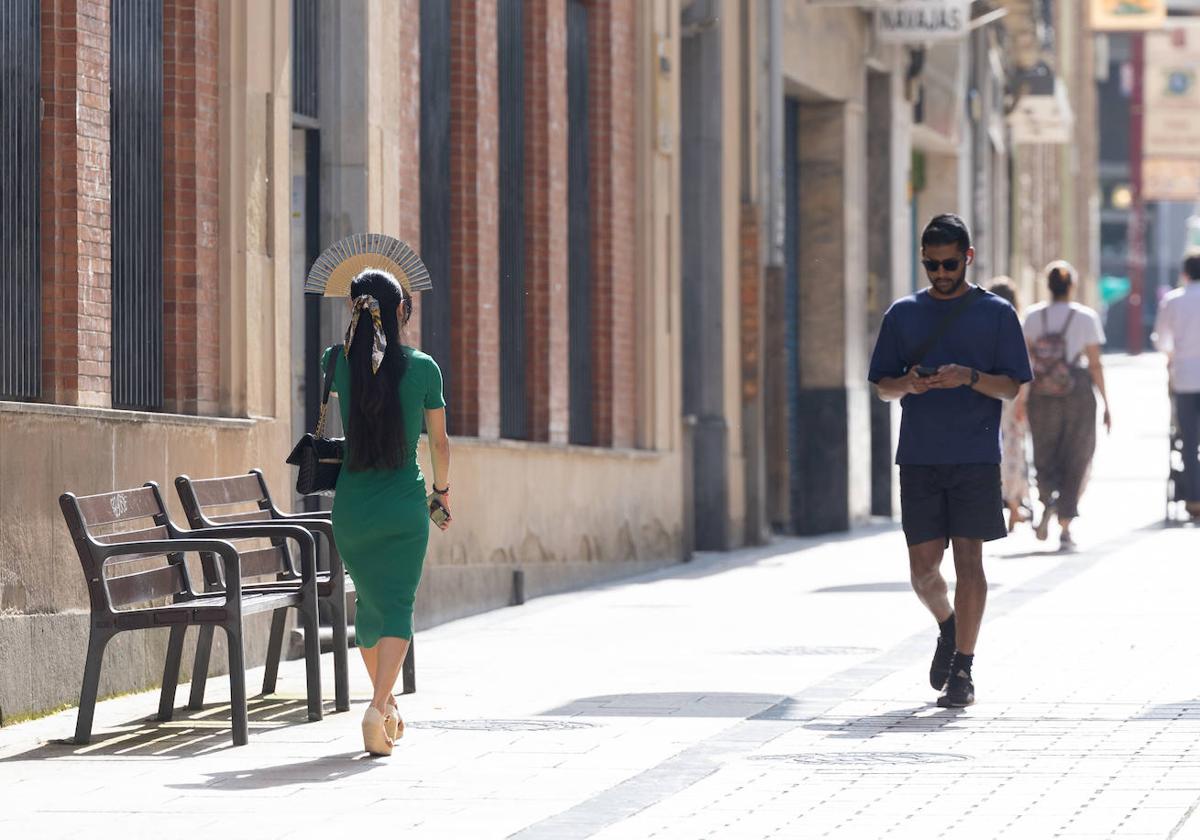 Una mujer se tapa con el abanico para protegerse del sol.