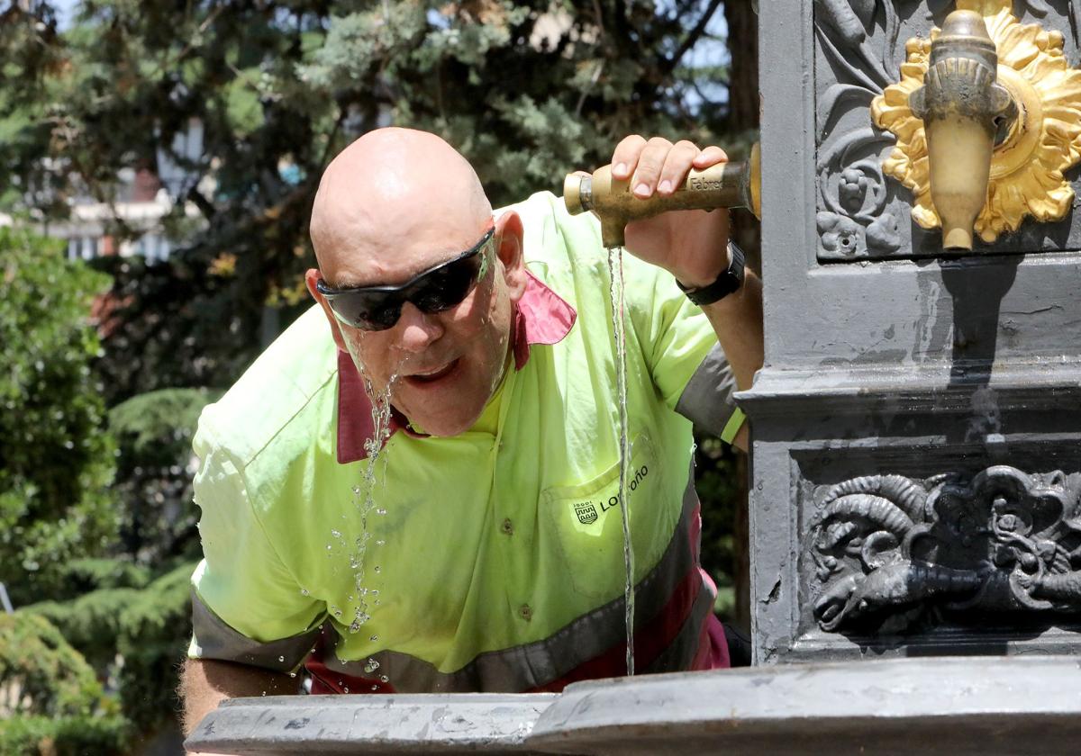 Un jardinero municipal se refresca en de las fuentes del Espolón logroñés