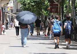 Una mujer trata de resguardarse del sol con un paraguas.