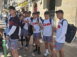 Un grupo de jugadores de la selección de China esperan en la parada del autobús urbano.