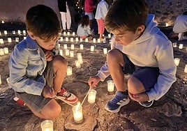 Dos niños encienden unas mechas durante la celebración, el sábado, de la Noche de las Velas.