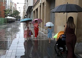 Ciudadanos paseando bajo la lluvia en una calle de Logroño.