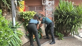 Dos asgentes colocan una corona en memoria a las víctimas.