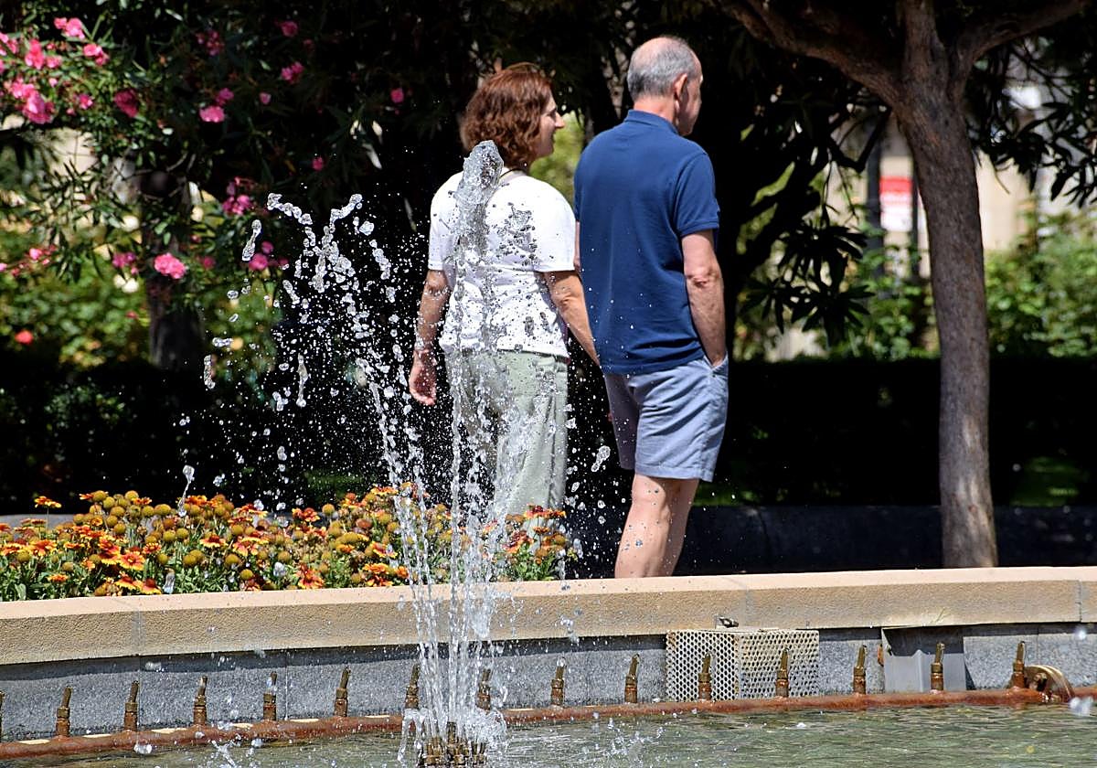 Dos personas pasean por El Espolón logroñés bajo el sol.