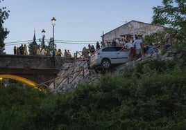 Varias personas ayudan para evitar que el vehículo caiga al río Leza.