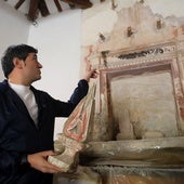 Pedro Muro, alcalde de Clavijo, señala el retablo oculto que ha sido descubierto en la ermita de San Román mientras porta en la mano una parte del retablo barroco que estaba a la vista.