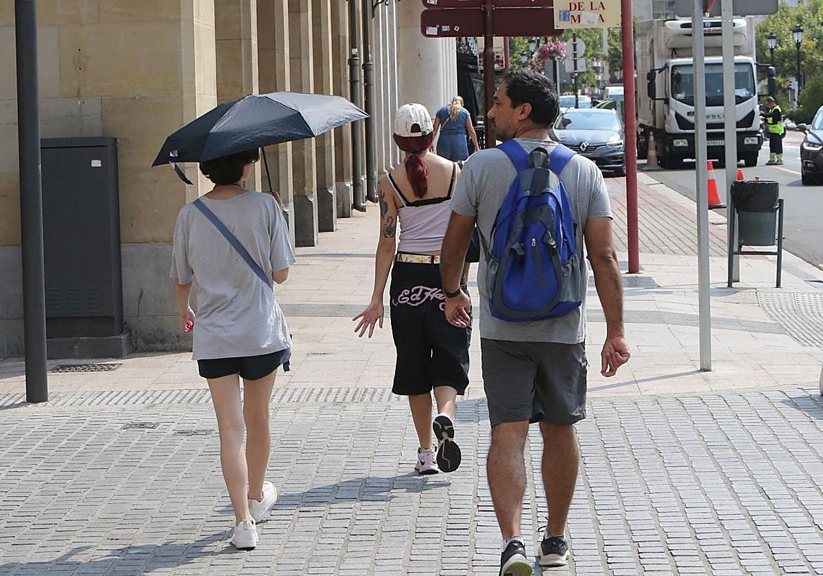 Una transeúnte se protege del sol con un paraguas.